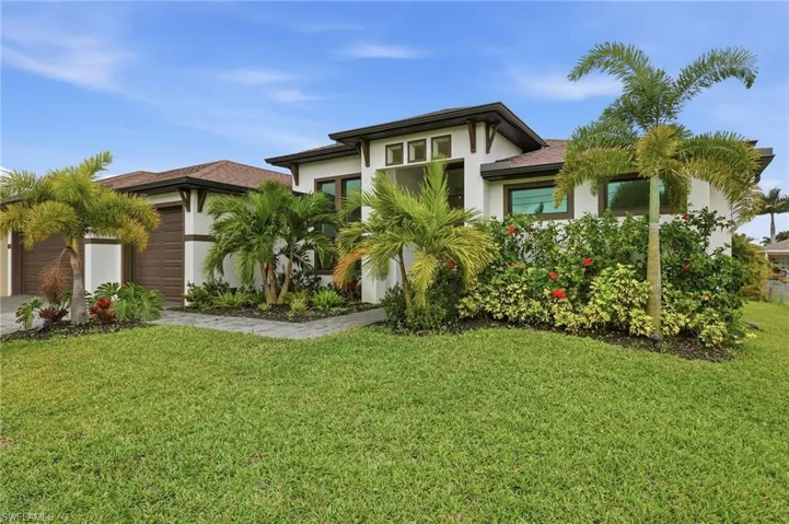 View of front facade with a front yard, stucco siding, driveway, and an attached garage