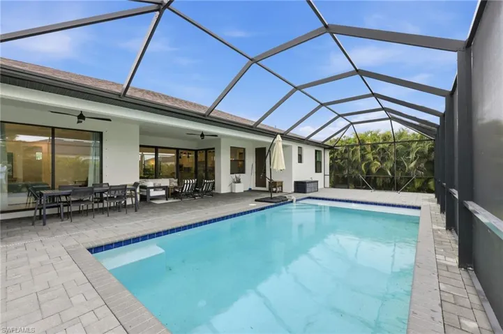 Outdoor pool with a sunroom, outdoor dining space, a lanai, and a patio