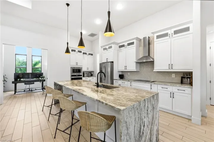 Kitchen featuring a kitchen bar, light stone counters, wood tiled floors, white cabinetry, and recessed lighting