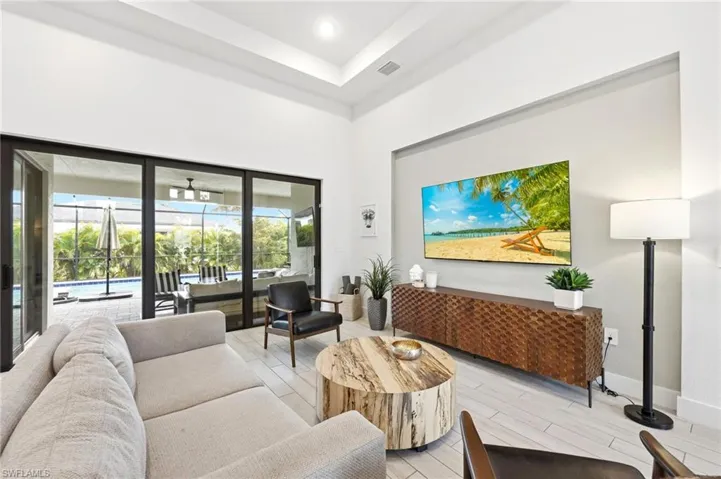 Living area featuring a high ceiling, wood tiled floors, a sunroom, and recessed lighting