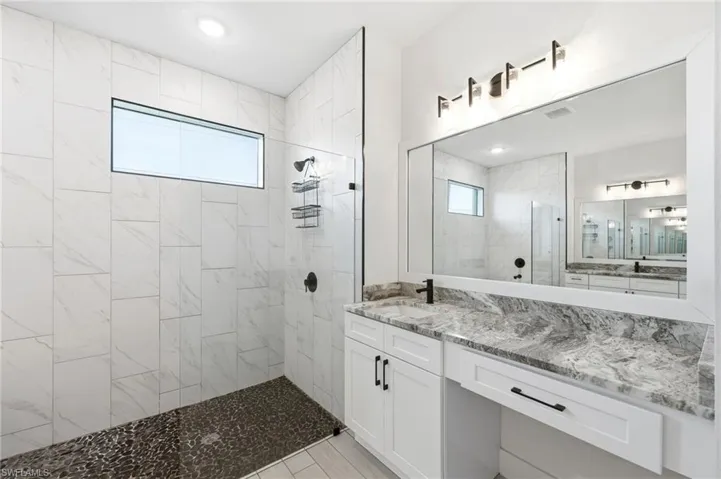 Bathroom featuring a walk in shower, vanity, and recessed lighting