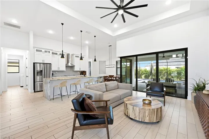 Living area featuring wood finish floors, a towering ceiling, recessed lighting, ceiling fan, and a tray ceiling