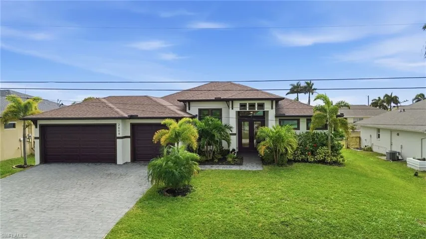 View of front facade with french doors, a front lawn, decorative driveway, an attached garage, and a shingled roof
