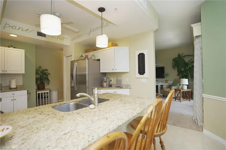 Kitchen with a kitchen bar, stainless steel refrigerator with ice dispenser, sink, and white cabinetry