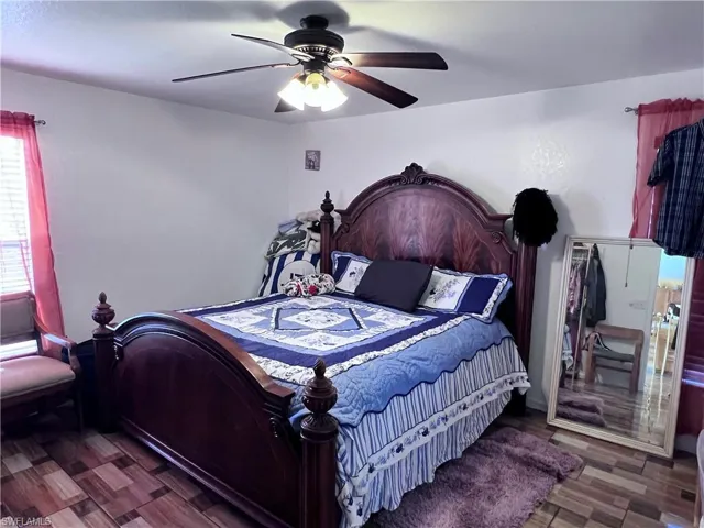 Bedroom with a ceiling fan and dark wood-type flooring