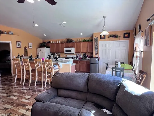 Living area with lofted ceiling, a ceiling fan, and recessed lighting