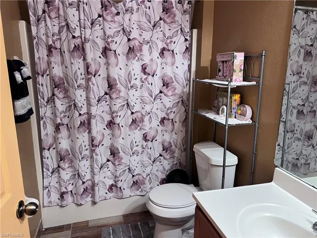 Full bathroom featuring vanity, a textured wall, shower / bath combo, and wood finished floors