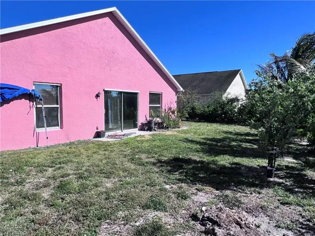 Back of property with stucco siding and a lawn