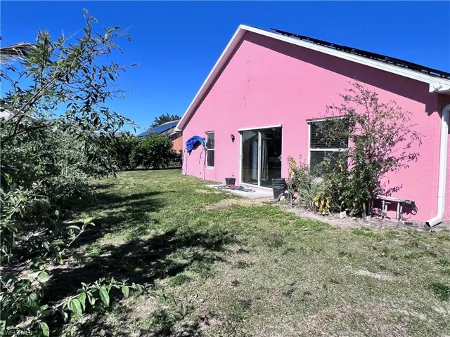 Back of property with a lawn and stucco siding