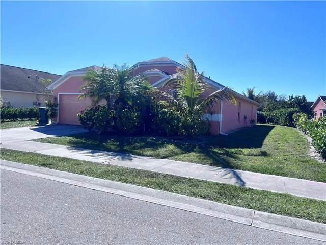View of front facade featuring a front yard, concrete driveway, stucco siding, and an attached garage