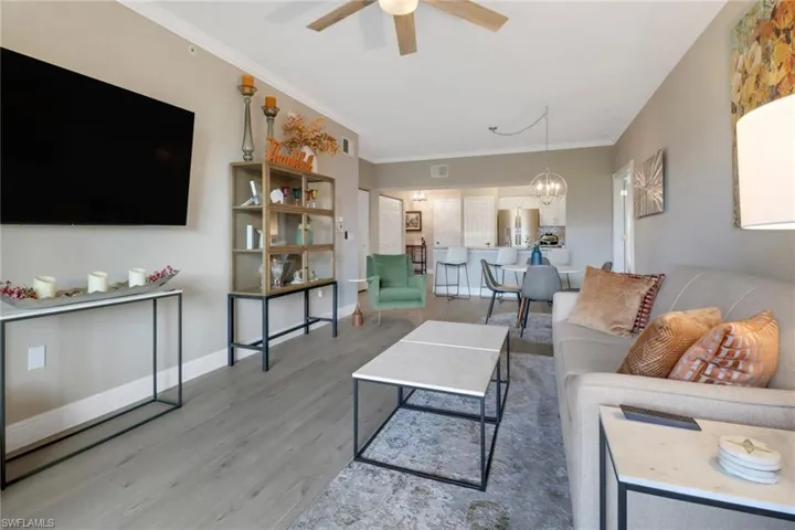 Living room with ornamental molding, ceiling fan with notable chandelier, and hardwood / wood-style flooring