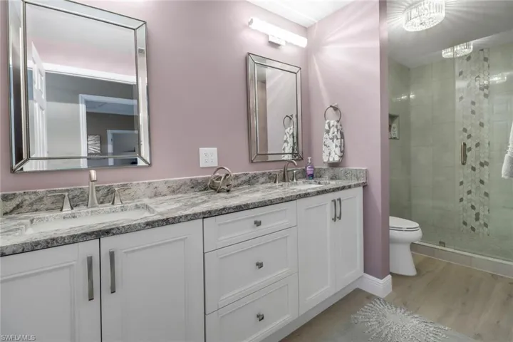 Bathroom featuring toilet, wood-type flooring, an enclosed shower, and double vanity