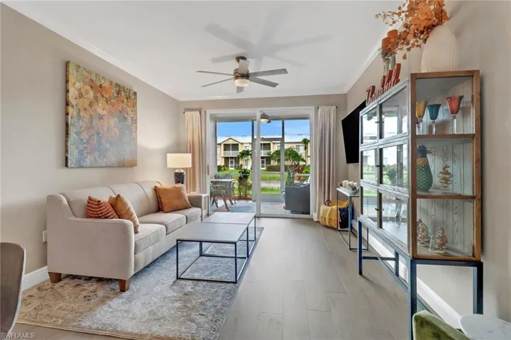 Living room featuring light wood-type flooring, ceiling fan, and ornamental molding