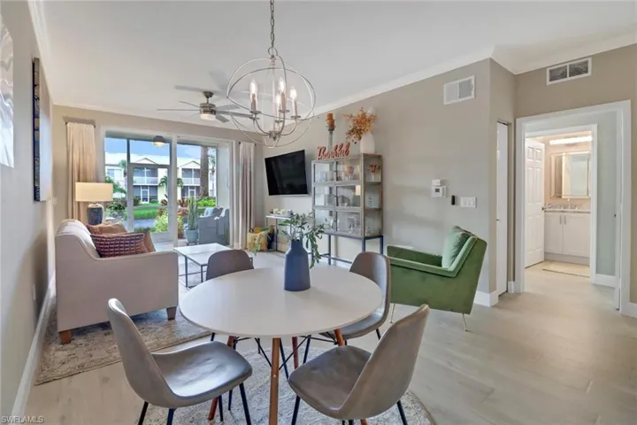 Dining area featuring ceiling fan with notable chandelier, crown molding, and light wood-type flooring