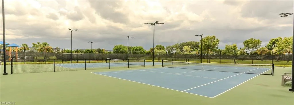 Dual hard-surface tennis courts featuring perimeter fencing and overhead athletic lighting