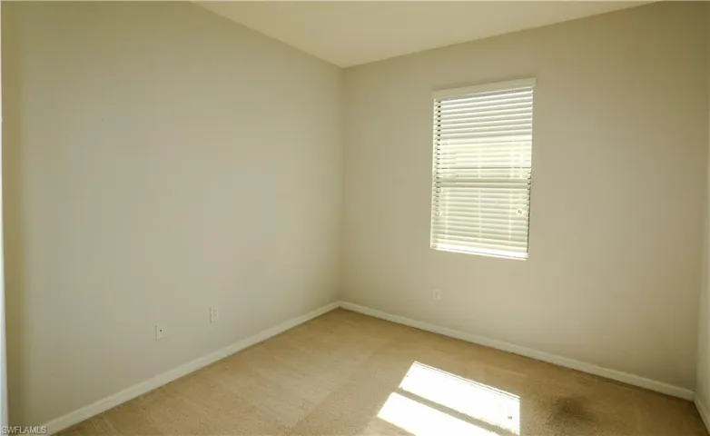 Neutral-toned interior room featuring wall-to-wall carpeting and a single window equipped with horizontal blinds