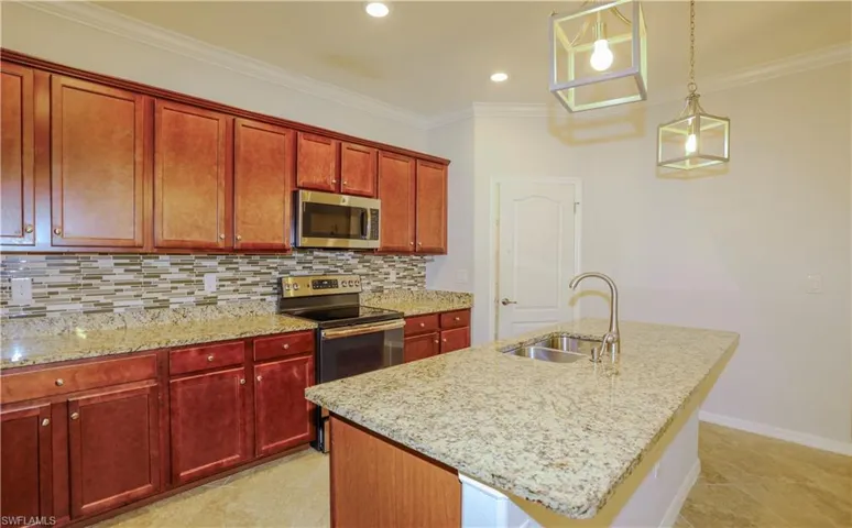 Kitchen featuring wood cabinetry, stone countertops, multi-toned tile backsplash, stainless steel appliances, and dual geometric pendant lighting
