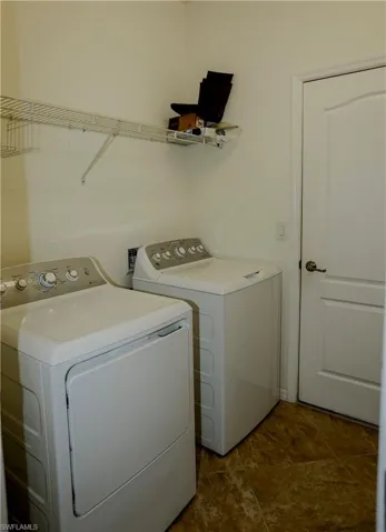 Laundry area featuring tile flooring, a white interior door with arched detailing, and wire shelving