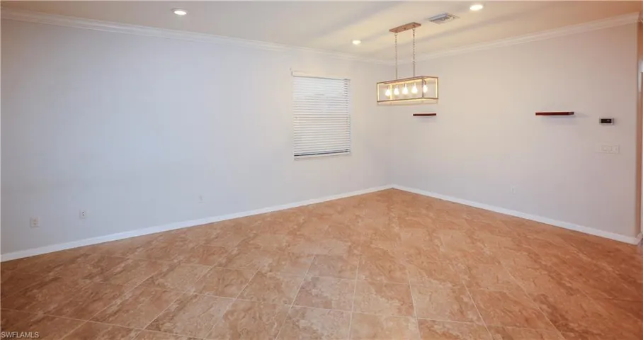 Large-format tile flooring, recessed ceiling lighting, a rectangular metal-frame pendant light fixture, crown molding, and dual wall-mounted floating shelves