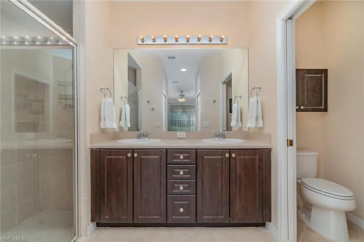 Bathroom with vanity, a shower with door, tile patterned floors, ceiling fan, and toilet