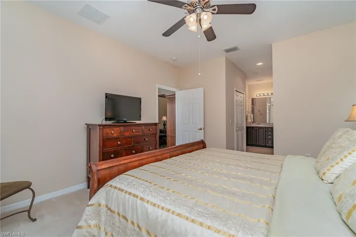 Bedroom featuring ceiling fan, light carpet, connected bathroom, and a closet