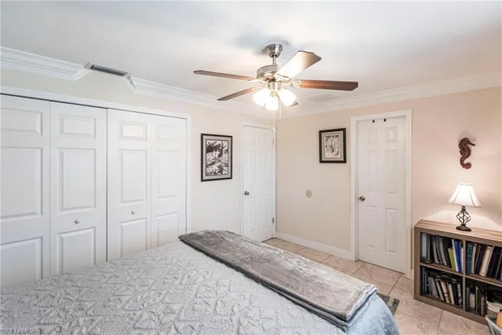 Bedroom featuring crown molding, a closet, ceiling fan, and light tile patterned floors