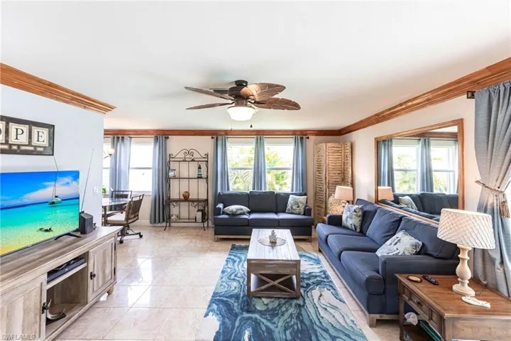 Living area with plenty of natural light, ornamental molding, and a ceiling fan