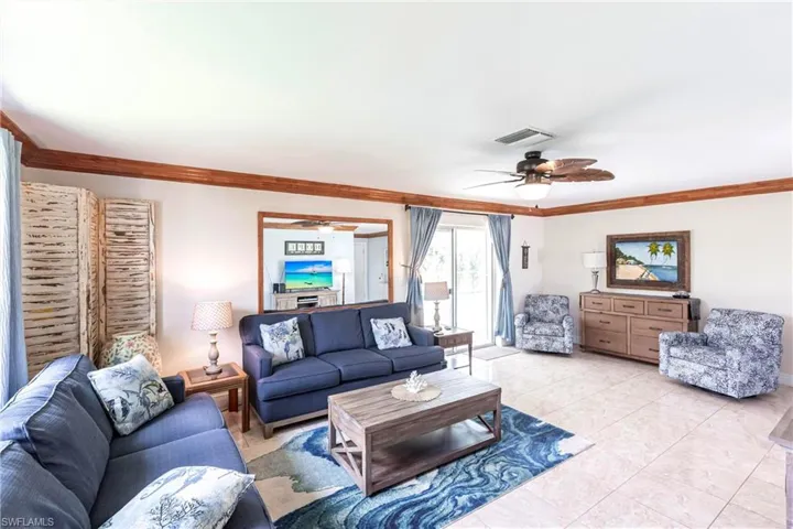 Living area featuring a ceiling fan, ornamental molding, and light tile patterned flooring