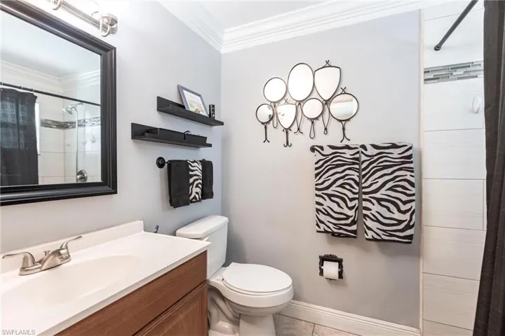 Full bathroom with crown molding, vanity, curtained shower, and tile patterned flooring
