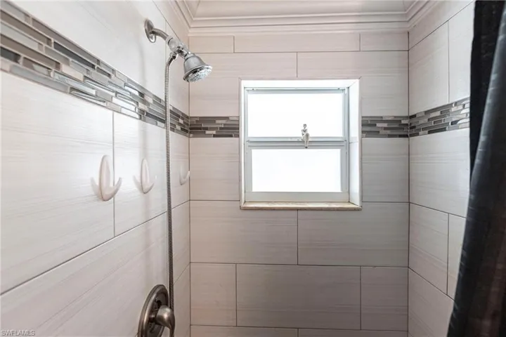 Full bath featuring a tile shower and ornamental molding