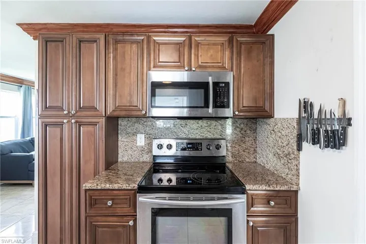 Kitchen with stainless steel appliances,  stone countertops, and tasteful backsplash