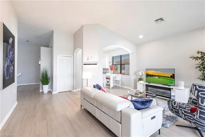 Living area featuring arched walkways, light wood-style floors, and recessed lighting