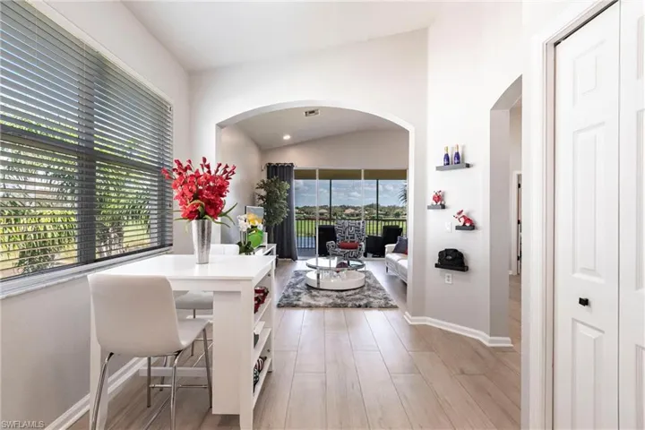 Dining area featuring arched walkways, healthy amount of natural light, lofted ceiling, and light wood-type flooring