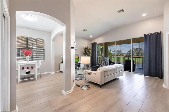 Living room featuring arched walkways, light wood-style flooring, plenty of natural light, lofted ceiling, and recessed lighting