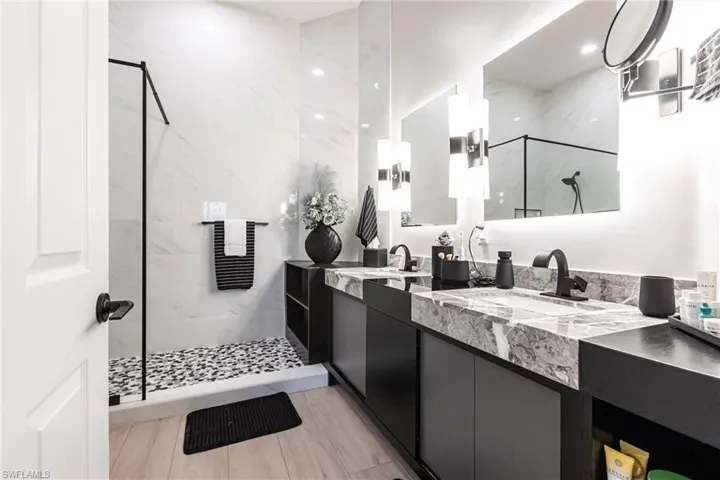 Bathroom with double vanity, a marble finish shower, and a towel warming rack