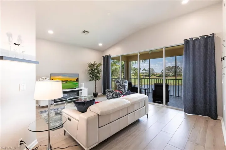 Living room with lofted ceiling, recessed lighting, and light wood finished floors