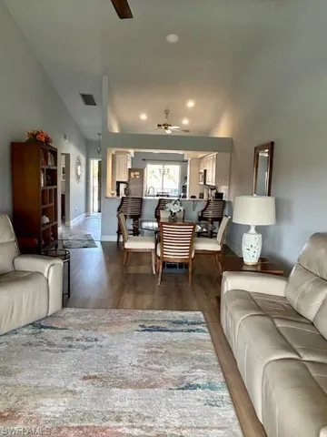 Living room with ceiling fan, dark wood finished floors, vaulted ceiling, and recessed lighting