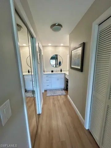 Bathroom with light wood-style flooring, vanity, and a closet