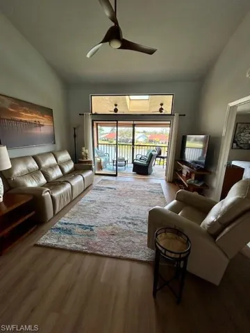 Living room featuring vaulted ceiling, wood finished floors, and ceiling fan