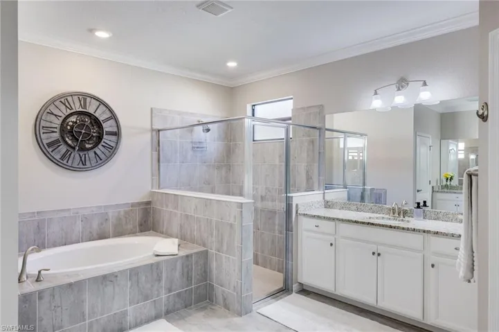 Full bathroom featuring vanity, a stall shower, ornamental molding, and a bath