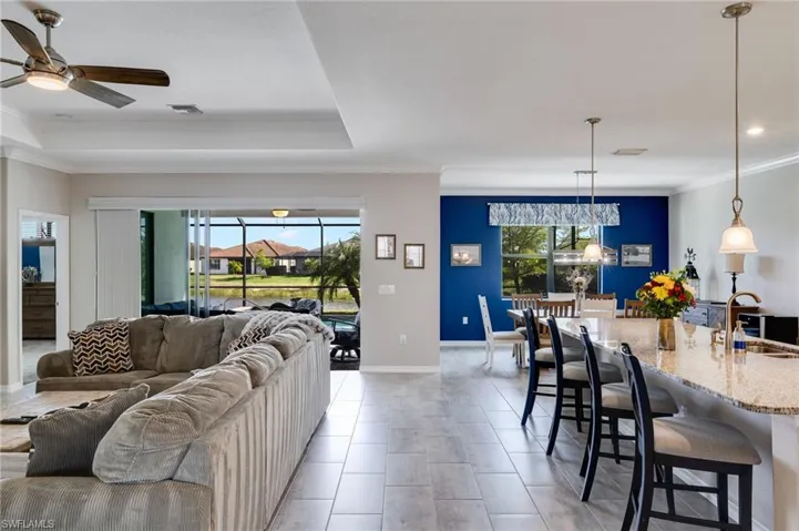 Living area featuring ceiling fan, crown molding, light tile patterned floors, and a tray ceiling