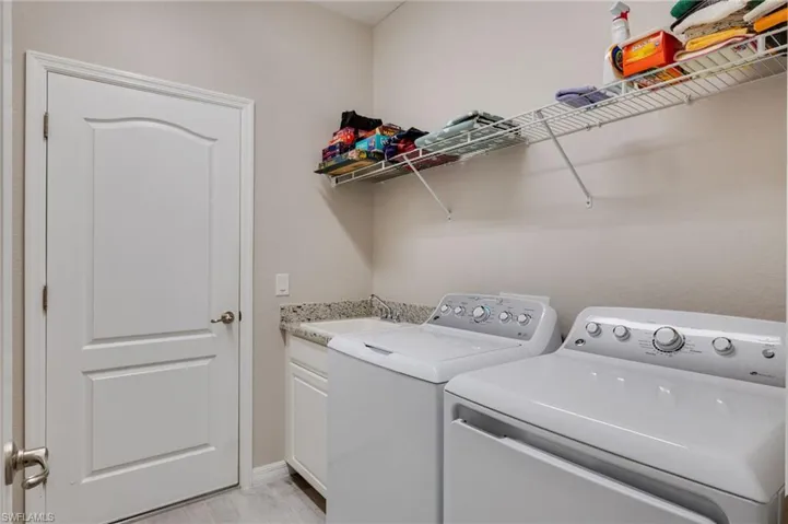 Laundry area with washing machine and clothes dryer and a sink