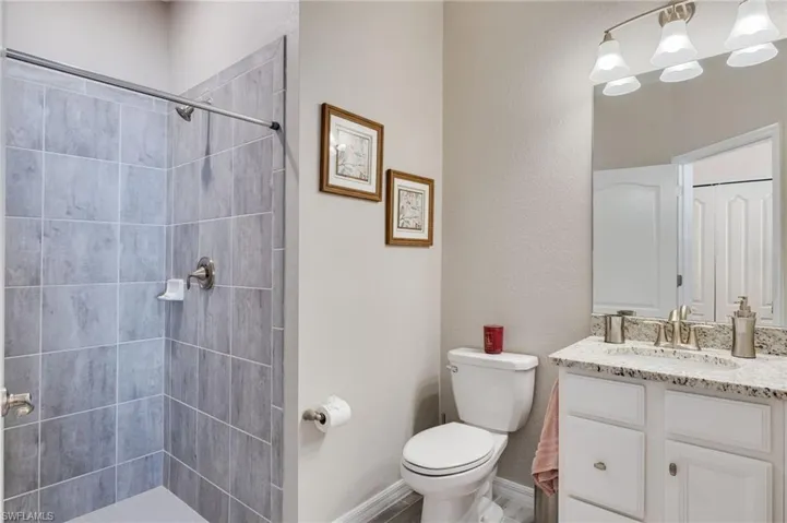 Full bathroom featuring a shower stall, vanity, and a textured wall