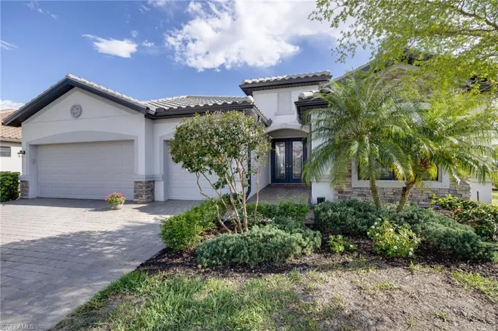 Mediterranean / spanish house with stone siding, french doors, decorative driveway, an attached garage, and stucco siding