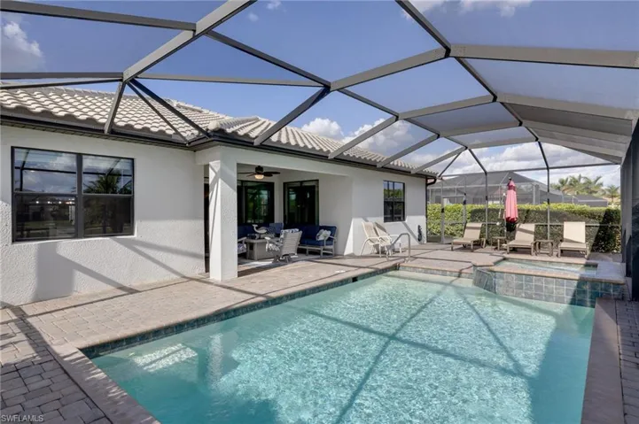 Integrated pool / hot tub featuring a patio, a sunroom, glass enclosure, and outdoor furniture