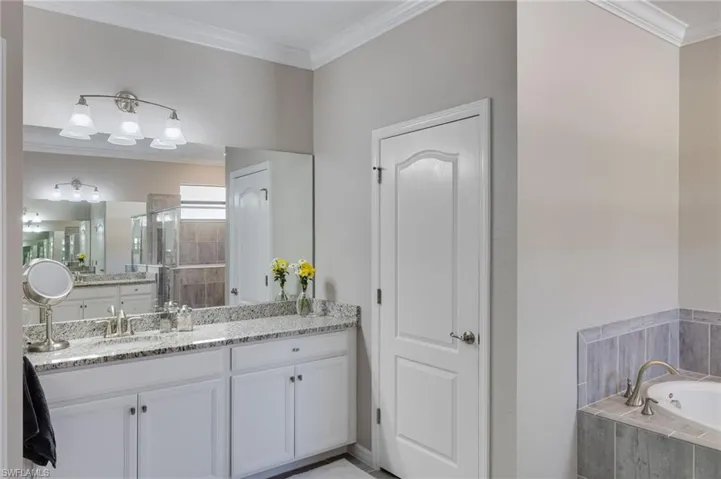 Full bathroom featuring ornamental molding, vanity, a shower stall, and a bath