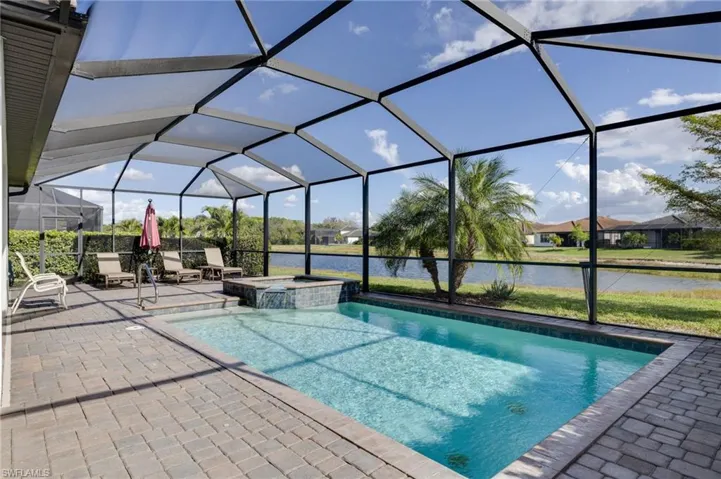 Integrated pool / hot tub with a sunroom, a water view, a lanai, and a patio