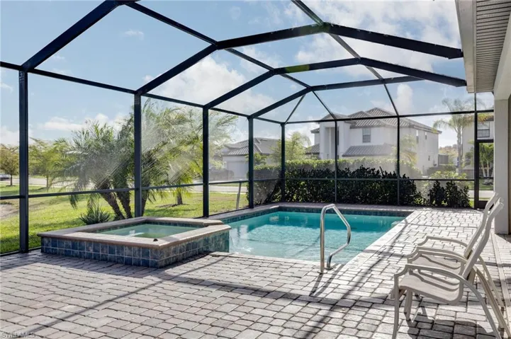 Relaxing pool / spa featuring a sunroom, a lanai, and a patio area