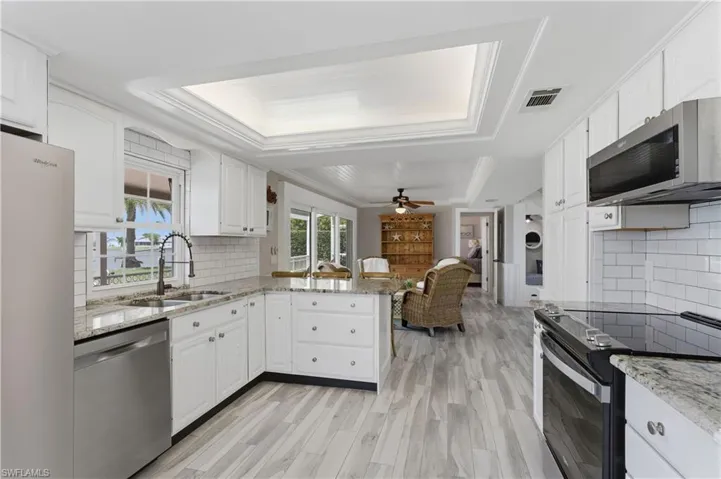 Kitchen featuring white cabinetry, granite countertops, stainless steel appliances, and wood-finish flooring