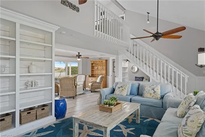 Open-concept living area featuring vaulted ceilings, wood-finish flooring, and a second-story interior balcony